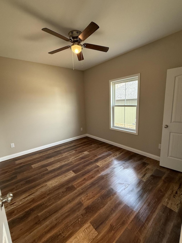 empty room with a ceiling fan, dark wood-style flooring, and baseboards