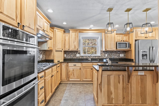 kitchen with sink, a kitchen island, backsplash, pendant lighting, and appliances with stainless steel finishes