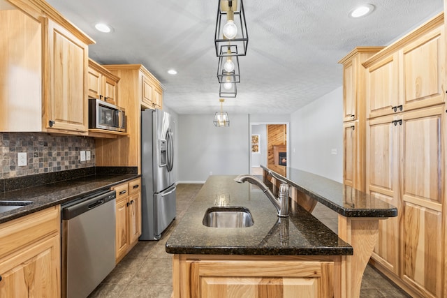 kitchen featuring stainless steel appliances, a center island with sink, sink, and pendant lighting