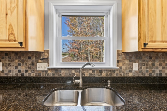 kitchen featuring a wealth of natural light, dark stone countertops, sink, and backsplash