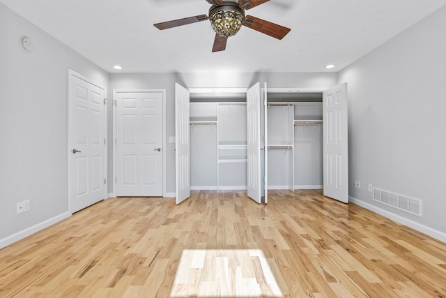 unfurnished bedroom with light hardwood / wood-style flooring, ceiling fan, and two closets