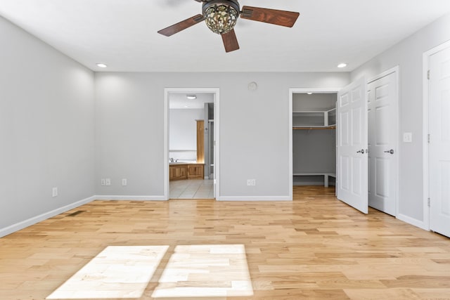 unfurnished bedroom featuring light hardwood / wood-style floors, ceiling fan, connected bathroom, and a spacious closet