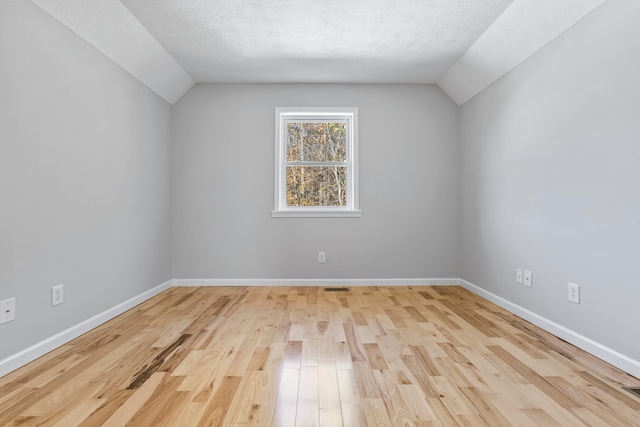 bonus room featuring light hardwood / wood-style floors, a textured ceiling, and vaulted ceiling