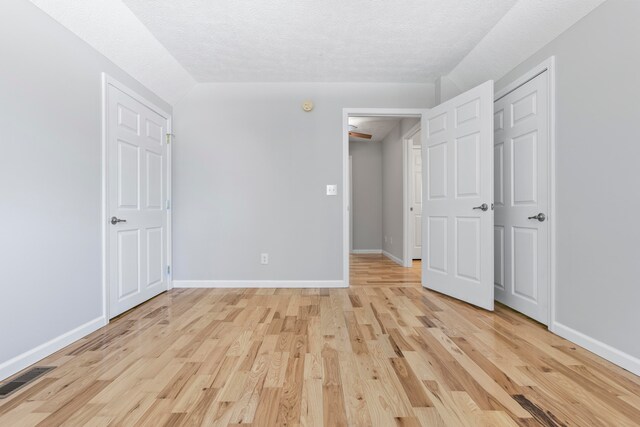 unfurnished bedroom with a textured ceiling and light wood-type flooring