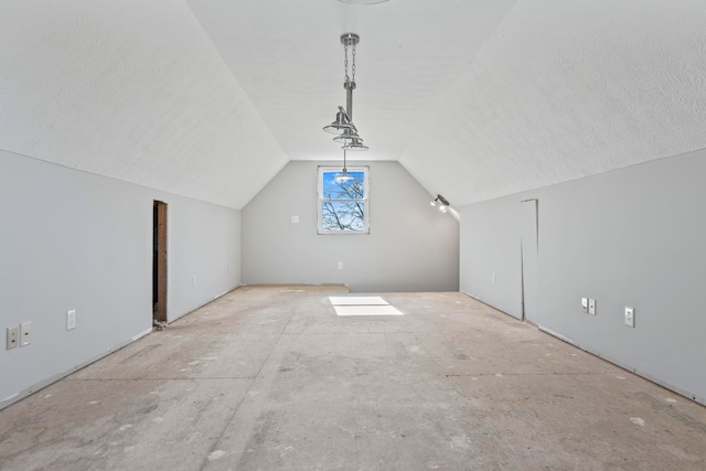 additional living space featuring a textured ceiling and vaulted ceiling