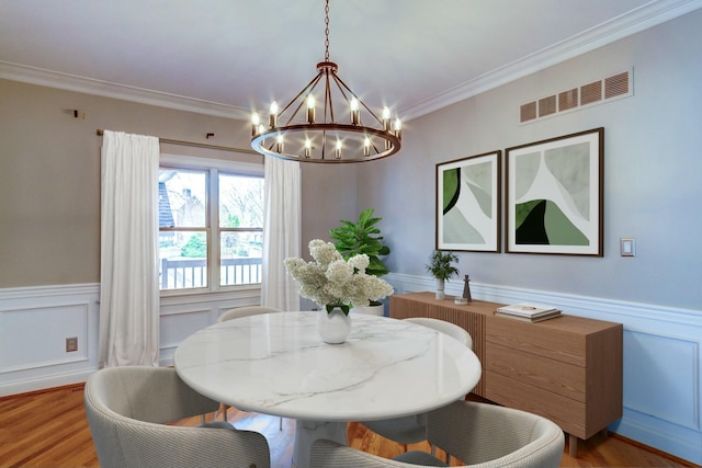 dining space with a chandelier, light hardwood / wood-style floors, and crown molding