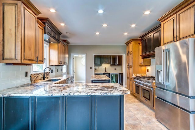 kitchen featuring light stone countertops, high end appliances, backsplash, and sink