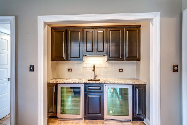 bar featuring wine cooler, tasteful backsplash, and dark brown cabinetry