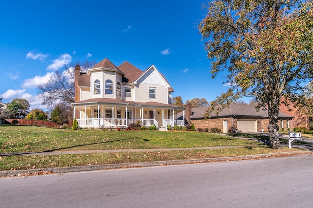 victorian house with covered porch, a front lawn, and a garage