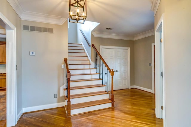 staircase with hardwood / wood-style floors, a chandelier, and ornamental molding