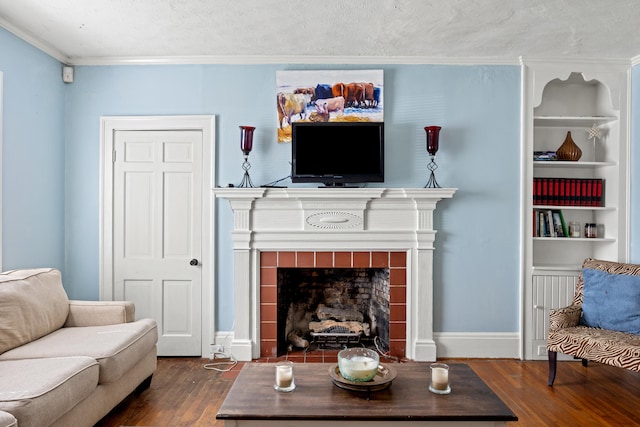 living room with ornamental molding, a tiled fireplace, a textured ceiling, and dark hardwood / wood-style floors