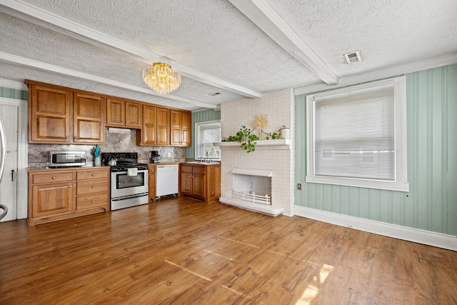 kitchen featuring wood-type flooring, a notable chandelier, a textured ceiling, beamed ceiling, and appliances with stainless steel finishes