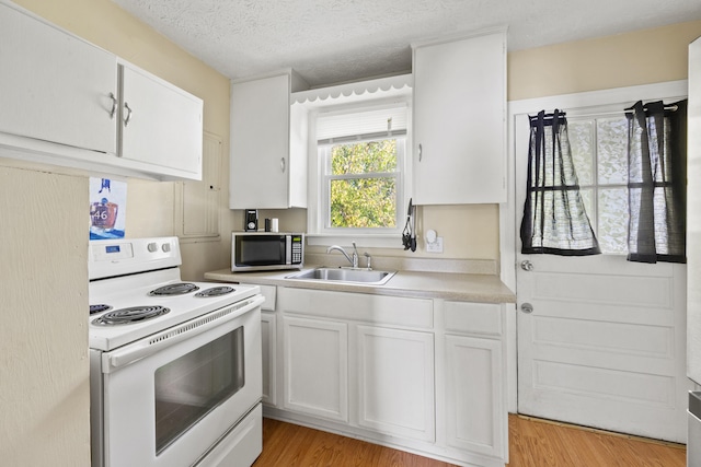 kitchen with light hardwood / wood-style floors, white cabinetry, sink, white range with electric stovetop, and a textured ceiling