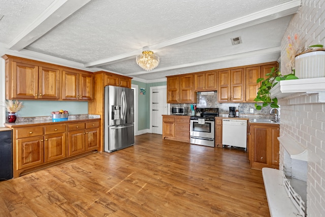 kitchen featuring light wood-type flooring, appliances with stainless steel finishes, a textured ceiling, beam ceiling, and a chandelier