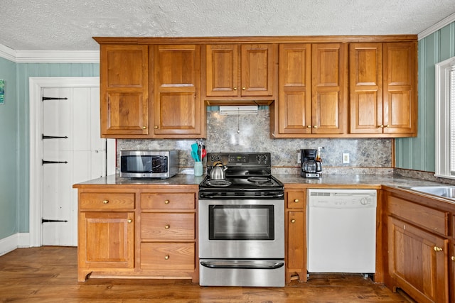 kitchen featuring dark wood-type flooring, appliances with stainless steel finishes, a textured ceiling, and ornamental molding