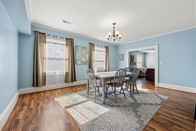 dining space featuring ornamental molding, wood-type flooring, and an inviting chandelier