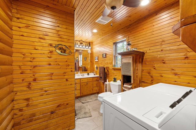 bathroom with wooden ceiling, wooden walls, tile patterned flooring, toilet, and washer and dryer