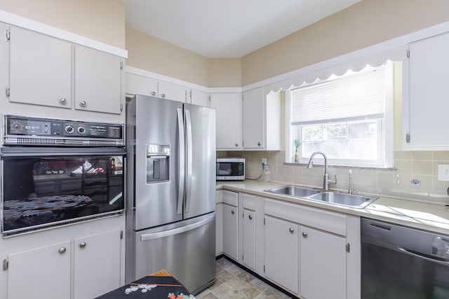 kitchen with decorative backsplash, white cabinets, sink, and stainless steel appliances