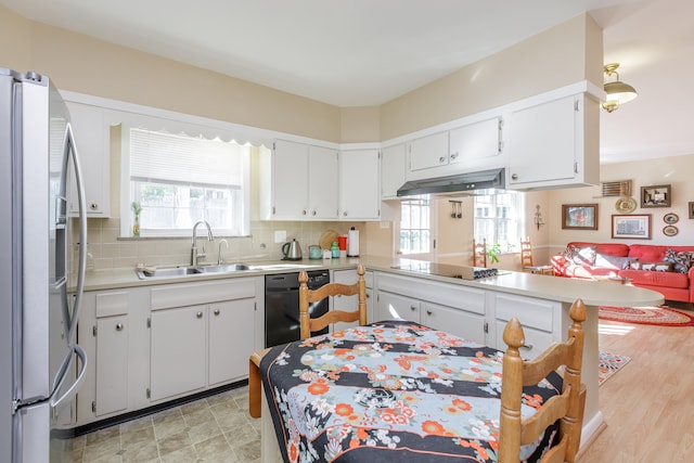 kitchen with a healthy amount of sunlight, stainless steel refrigerator with ice dispenser, kitchen peninsula, and sink