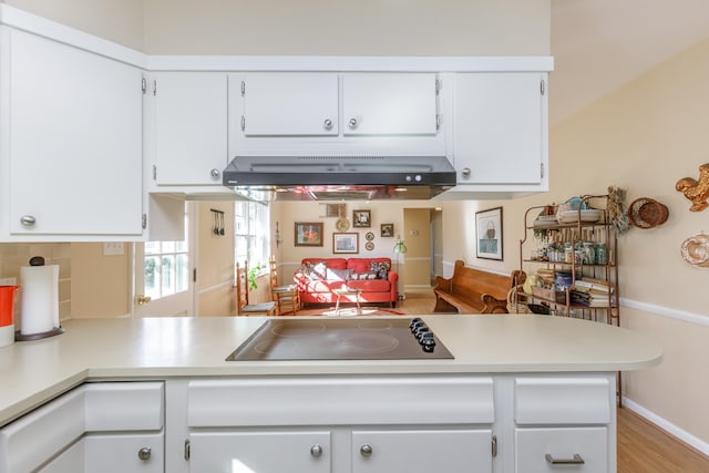 kitchen with light hardwood / wood-style floors, black electric stovetop, kitchen peninsula, extractor fan, and white cabinetry