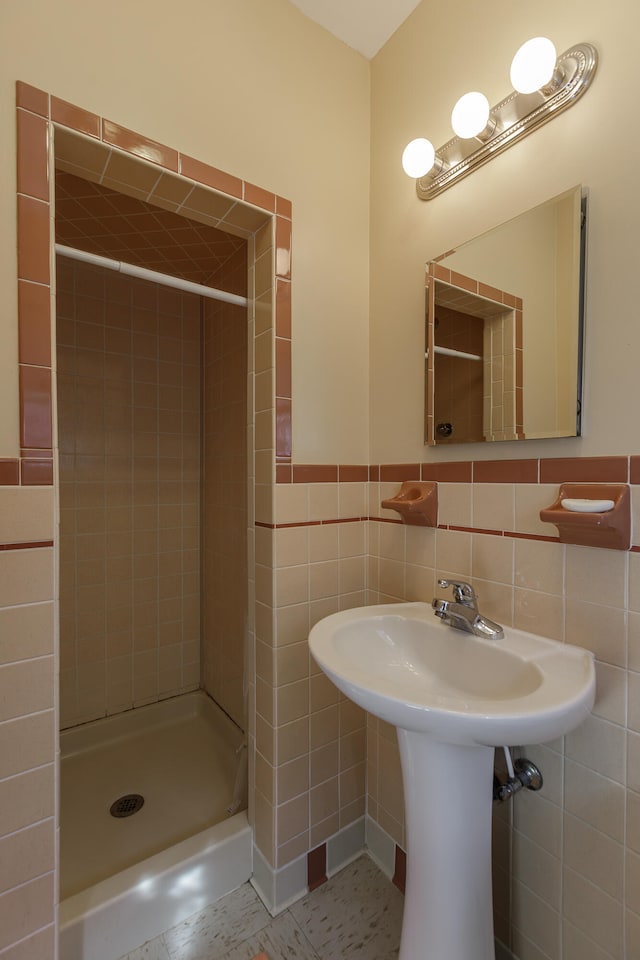 bathroom featuring tile patterned floors, tiled shower, and tile walls