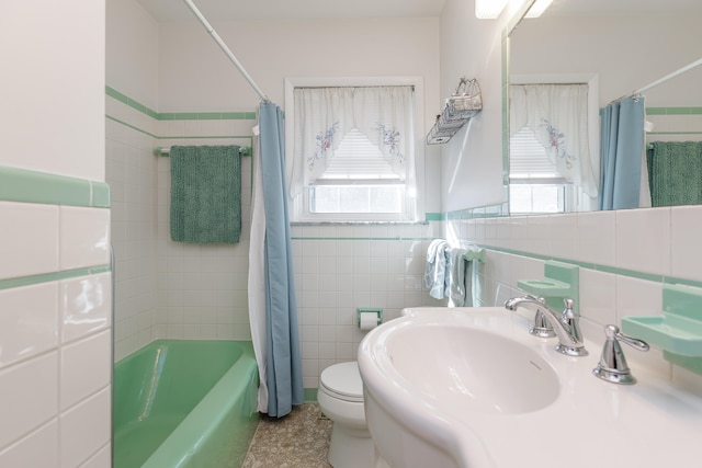 full bathroom featuring sink, shower / bath combination with curtain, toilet, and tile walls