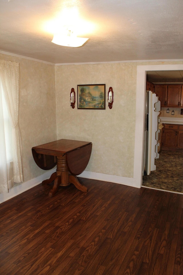 dining room featuring dark wood-type flooring, a textured ceiling, and ornamental molding