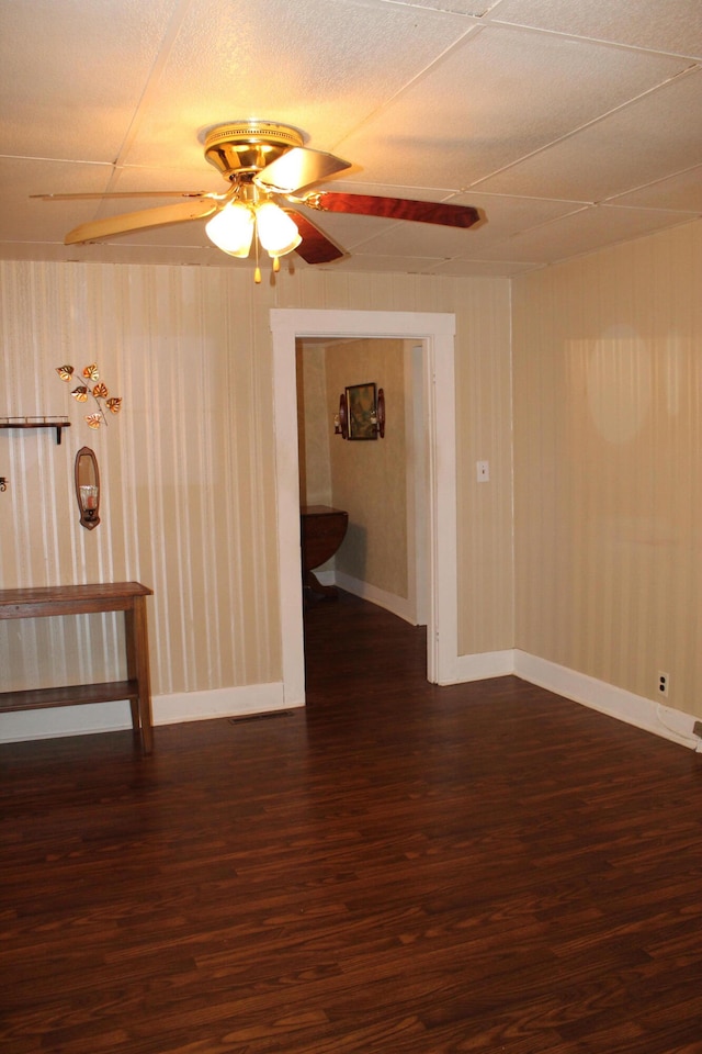 empty room with ceiling fan, dark hardwood / wood-style floors, and wooden walls