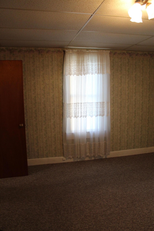 carpeted spare room featuring a drop ceiling