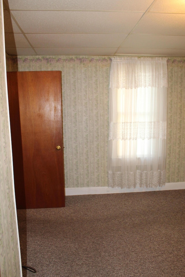 unfurnished room featuring a paneled ceiling and carpet flooring