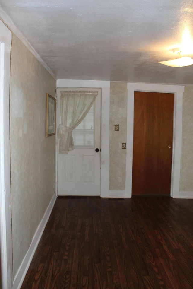 hall with dark wood-type flooring and a textured ceiling