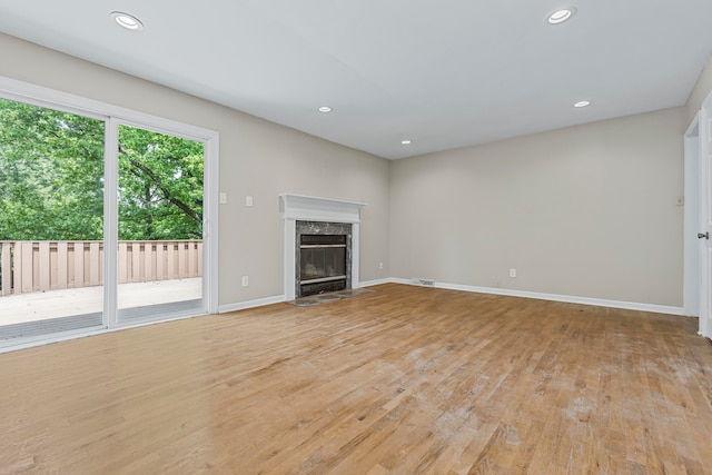 unfurnished living room with a high end fireplace and light wood-type flooring