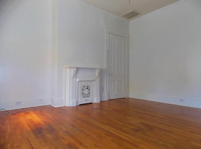 unfurnished living room featuring wood-type flooring and ornamental molding