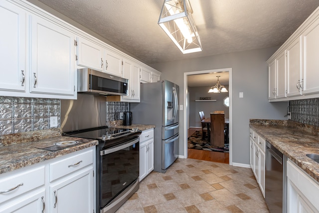 kitchen featuring white cabinetry, stainless steel appliances, a textured ceiling, and pendant lighting