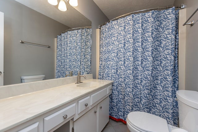 bathroom featuring toilet, vanity, a textured ceiling, and tile patterned floors