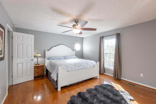 bedroom featuring hardwood / wood-style floors, ceiling fan, and a textured ceiling