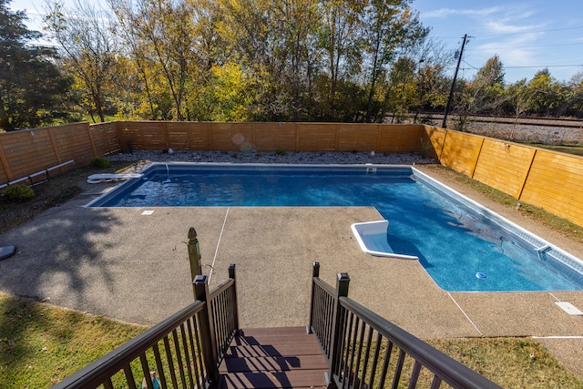 view of pool with a diving board and a patio area