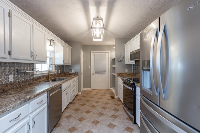 kitchen featuring white cabinetry, sink, appliances with stainless steel finishes, tasteful backsplash, and a textured ceiling