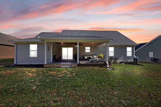 back house at dusk featuring central AC, a patio area, a yard, and ceiling fan