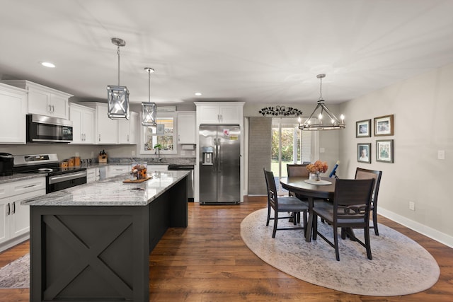 kitchen featuring stainless steel appliances, hanging light fixtures, a healthy amount of sunlight, and a center island