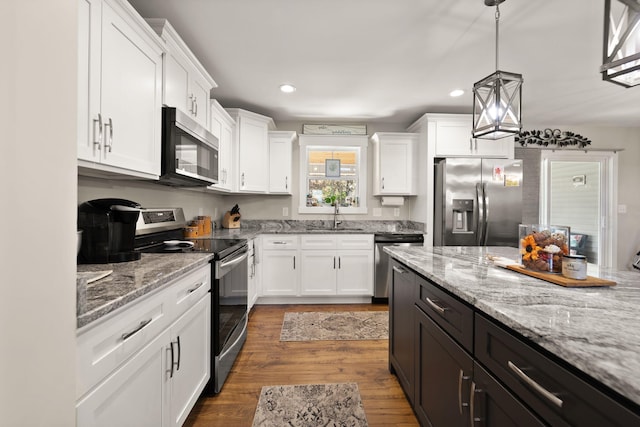 kitchen featuring dark hardwood / wood-style flooring, white cabinetry, appliances with stainless steel finishes, and decorative light fixtures