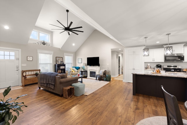 living room featuring high vaulted ceiling, beamed ceiling, wood-type flooring, and ceiling fan