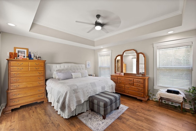 bedroom with hardwood / wood-style flooring, ceiling fan, and a raised ceiling