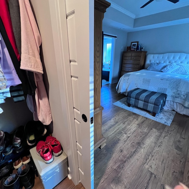 bedroom with dark wood-type flooring, ceiling fan, and crown molding