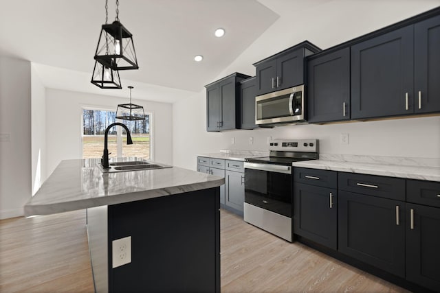 kitchen with appliances with stainless steel finishes, decorative light fixtures, sink, vaulted ceiling, and a kitchen island with sink