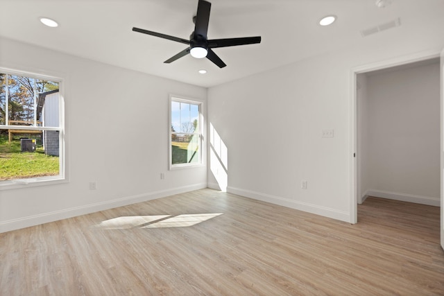 unfurnished room featuring a wealth of natural light, ceiling fan, and light hardwood / wood-style floors