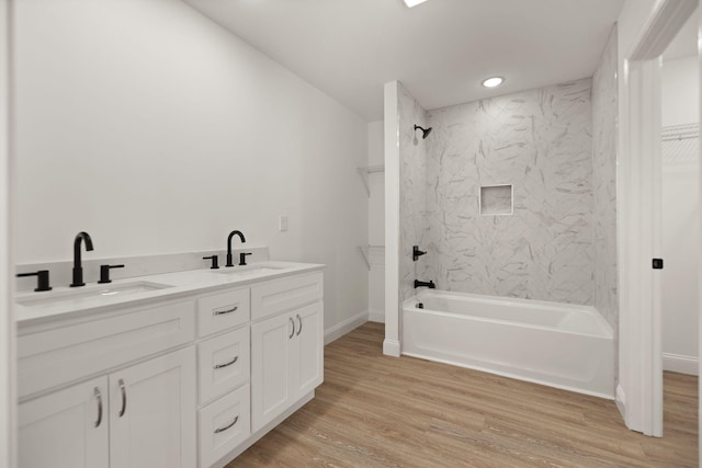 bathroom with tiled shower / bath, vanity, and wood-type flooring