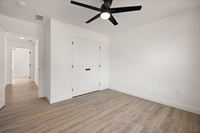 unfurnished bedroom with light wood-type flooring, ceiling fan, and a closet