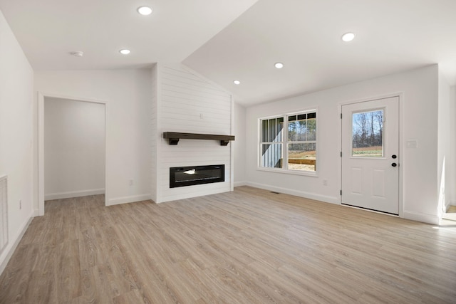 unfurnished living room featuring light wood-type flooring, vaulted ceiling, and a fireplace