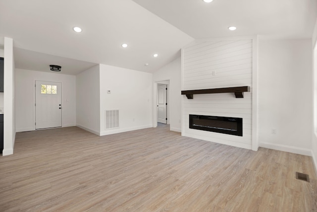 unfurnished living room featuring light hardwood / wood-style floors, a large fireplace, and lofted ceiling